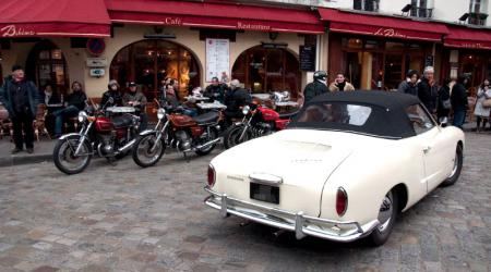 Volkswagen Karmann Ghia blanche vue de 3/4 arrière droit avec de vieilles motos en arrière plan